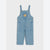A pair of light blue denim baby overalls with adjustable shoulder straps, front patch pockets, and a small embroidered yellow bear face patch on the chest, shown flat against a light gray background.