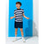 A young boy modeling a navy blue and white striped short-sleeve t-shirt with matching navy shorts, white socks, and white sneakers, standing against a bright blue and white studio backdrop.