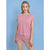 A woman modeling a pink short-sleeve crewneck t-shirt and matching pink patterned shorts against a solid blue background.