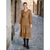 A woman stands in a narrow cobblestone alley wearing a long-sleeve tiered midi dress in a warm camel brown color, paired with black knee-high boots.
