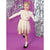 A young girl posing in a white long-sleeve top with gold star graphics and a sparkly champagne-gold sequined skirt, set against a purple background with silver tinsel and a disco ball.