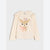 A cream-colored long-sleeve girls' top with ruffled shoulder details and a central graphic of a cute deer with pink flowers and the text 'cute & cozy'.