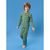 A young boy wearing a two-piece long-sleeve pajama set with an all-over dinosaur print, standing against a solid blue studio background.