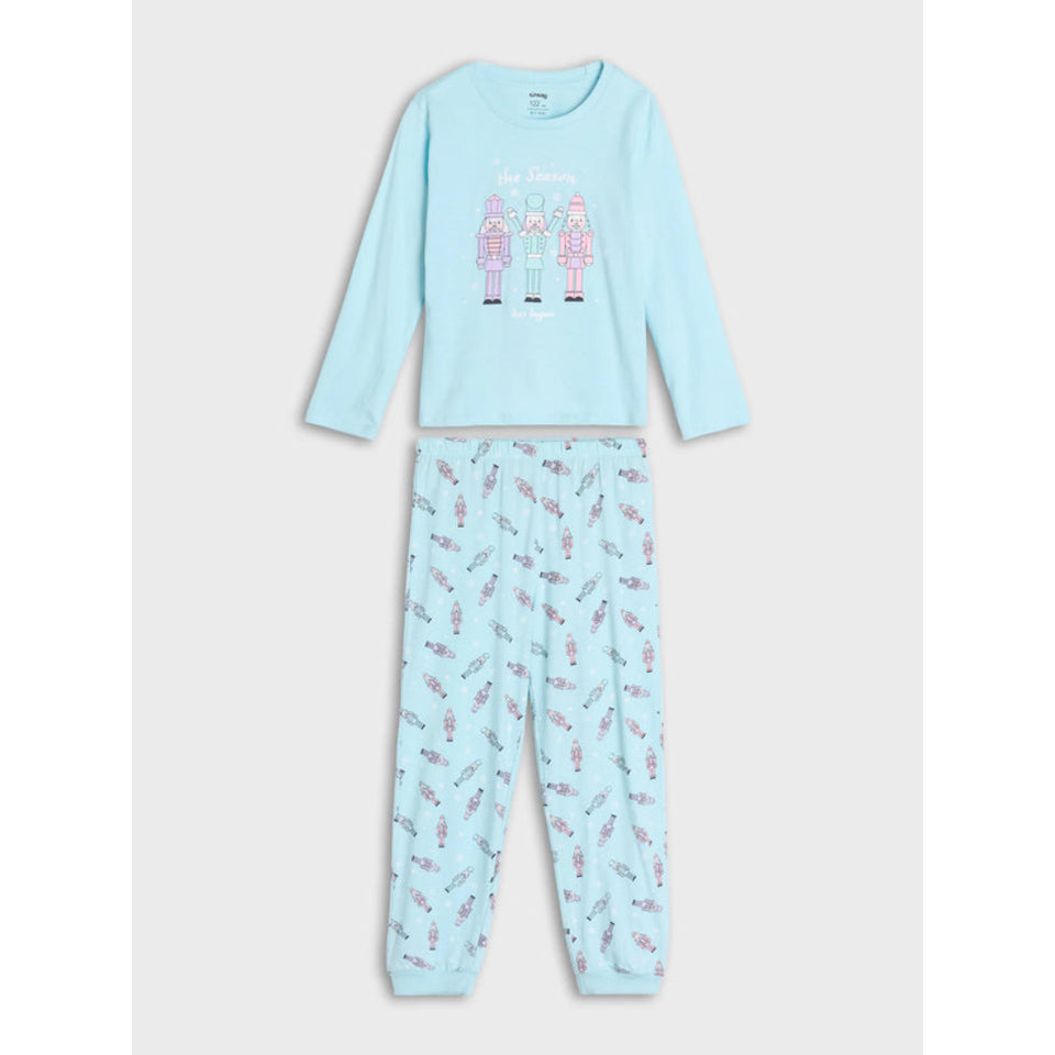 A two-piece children's pajama set in light blue, featuring a long-sleeve top with a graphic of three girls and the text 'The Dreamers' on the chest, and matching patterned pants with small pink and red illustrations.