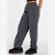 A person wearing loose dark gray wide-leg pants with an elastic waistband, paired with black slip-on shoes, shown from the waist down against a plain light background.