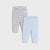 Two pairs of baby leggings laid flat on a light gray background: one pair is white with thin gray horizontal stripes, and the other is a solid pale blue. Each pair has a small white brand patch on the upper leg.