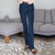 A person wearing dark blue high-waisted flare jeans, standing in a living room with a gray sofa and patterned rug.