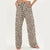 A pair of wide-leg pants with a brown and beige leopard print pattern, modeled from the waist down on a plain white background.