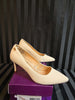 Beige high-heeled shoes on a purple box with a striped background