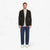 Man wearing a black blazer, gray shirt, blue jeans, and white sneakers on a white background