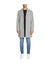 Person wearing a gray coat, black shirt, and blue jeans on a white background