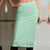 A woman wearing a mint green lace midi skirt with a sheer floral pattern and a lace hem, paired with black leather pants.