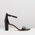 A single black patent leather block-heel sandal with an ankle strap and a slim toe strap, shown in profile against a light gray background.
