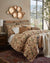 Decorative bedroom with floral bedding, pillows, and wall art.