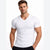 A muscular man wearing a fitted white short-sleeve V-neck t-shirt, shown from the waist up against a plain white studio background.