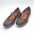 A pair of women's brown leather Mary Jane flats with a single strap and a small decorative button, shown on a white background.