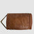 A brown faux-leather toiletry bag with a zippered closure and a small brand patch on the front, shown against a light gray background.
