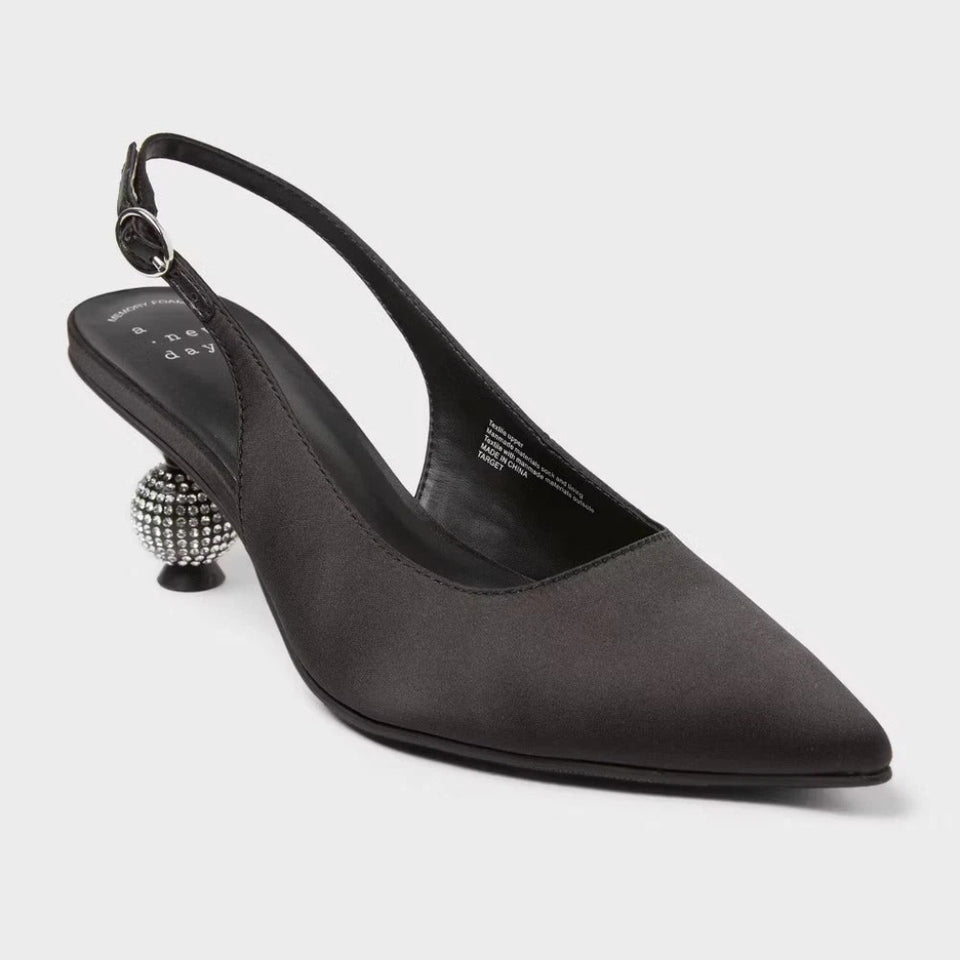 Black pointed-toe slingback pump with embellished heel on a light gray background