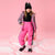 A young girl stands in a studio wearing a pink and black leopard-print ski jacket and matching pink ski pants, with a black beanie and black boots, against a solid pink background.