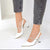 White slingback pointed-toe high heels with rhinestone-embellished straps, shown on a model wearing gray cuffed jeans against a clean white background.