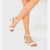 White ankle-strap block-heel sandals worn on a model's feet, shown against a clean white studio background.