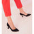 Black pointed-toe kitten heel pumps worn with bright red cropped trousers, shown on a model against a light pink studio background.