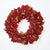 A festive artificial poinsettia wreath in deep red with metallic gold and olive green accents, photographed against a clean white background.