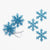 Five glittery blue snowflake ornaments with silver hanging ribbons, arranged on a plain white background.