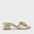 A metallic gold slide sandal with a block heel and a jeweled decorative embellishment on the front strap, shown from a side profile against a light gray background.