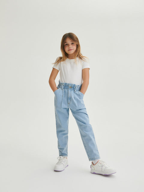 Child wearing light blue jeans and a white t-shirt on a white background