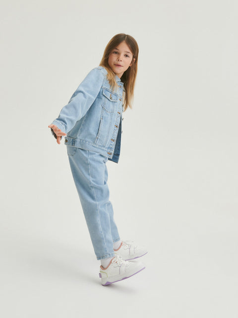 Person wearing a light blue denim jacket and jeans on a white background