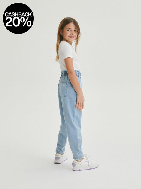 Young girl wearing a white t-shirt and light blue jeans on a white background