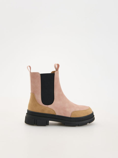 Two-tone pink and brown Chelsea boot with black sole on a white background