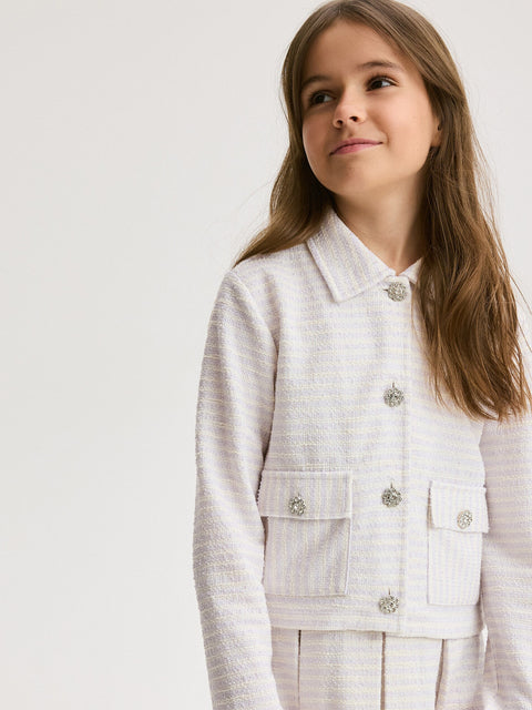 Young girl wearing a light gray textured jacket with decorative buttons on a white background