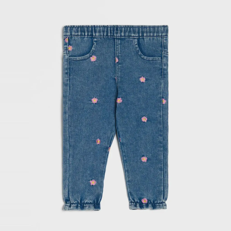 Blue denim baby leggings with small pink embroidered flowers, elastic waistband, and elastic ankle cuffs, shown flat on a light gray background.