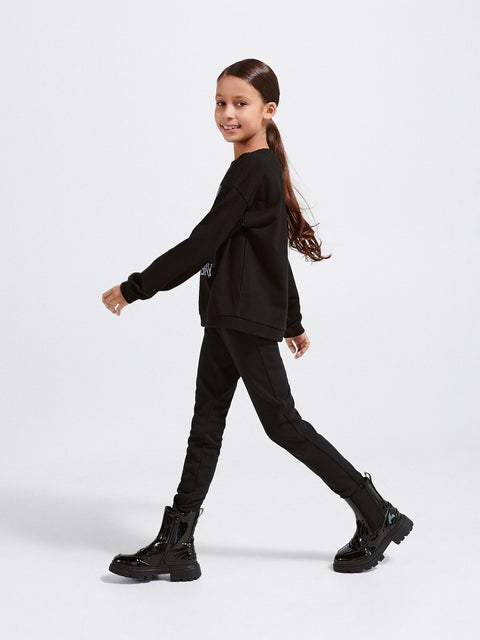 Girl wearing a black outfit with boots on a white background