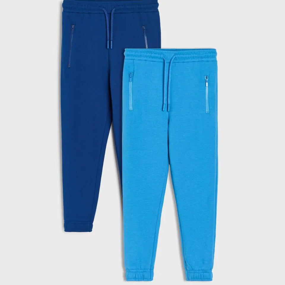 Two pairs of jogger sweatpants shown on a light gray background, one in dark blue and one in bright blue, both with drawstrings and zippered side pockets.