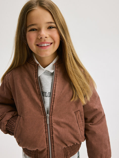 Young girl wearing a brown jacket on a white background