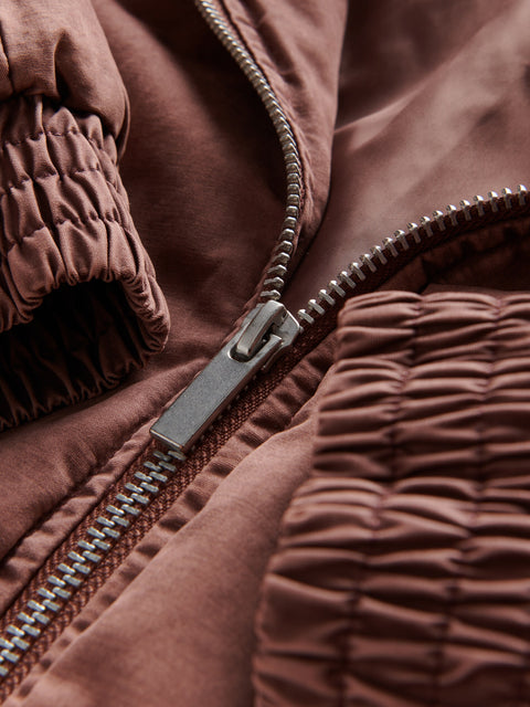 Close-up of a brown quilted jacket with a zipper