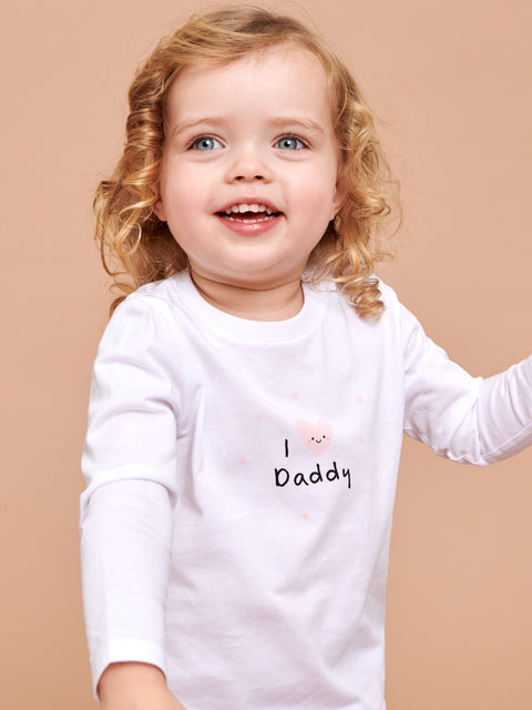 Child wearing a white shirt with 'I love Daddy' text on a beige background