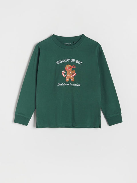 Green long-sleeve shirt with Christmas-themed graphic and text on a light gray background