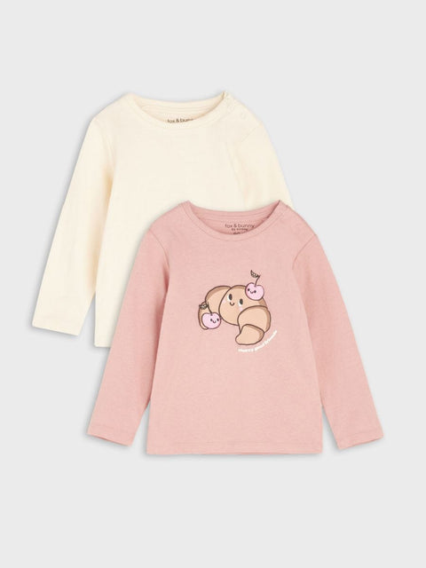 Two children's long-sleeve shirts, one cream and one pink with a design, on a light gray background.