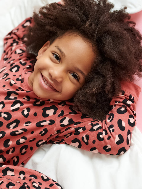 Child wearing a pink leopard print outfit lying on a white surface