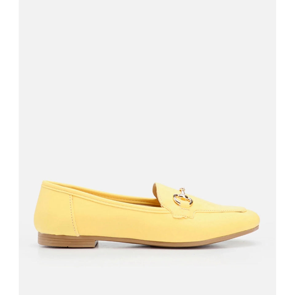A single yellow suede loafer flat with a small gold-tone horsebit detail on the vamp and a low tan block heel, shown in profile against a light gray background.