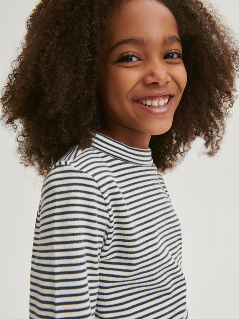 Child wearing a black and white striped shirt against a plain background