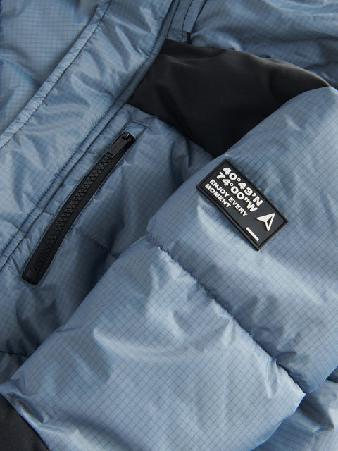 Close-up of a blue jacket with a visible brand patch on a textured fabric background