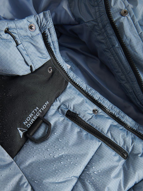 Close-up of a blue jacket with a visible brand logo, showing texture and details.