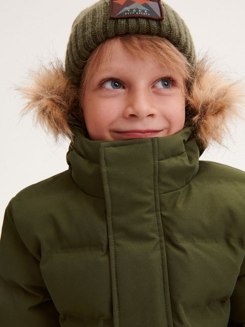 Child wearing a green winter coat with fur-lined hood on a plain background