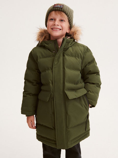 Child wearing a green winter coat with fur hood on a white background
