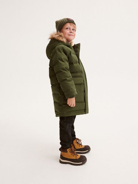 Child wearing a green coat with fur hood on a white background